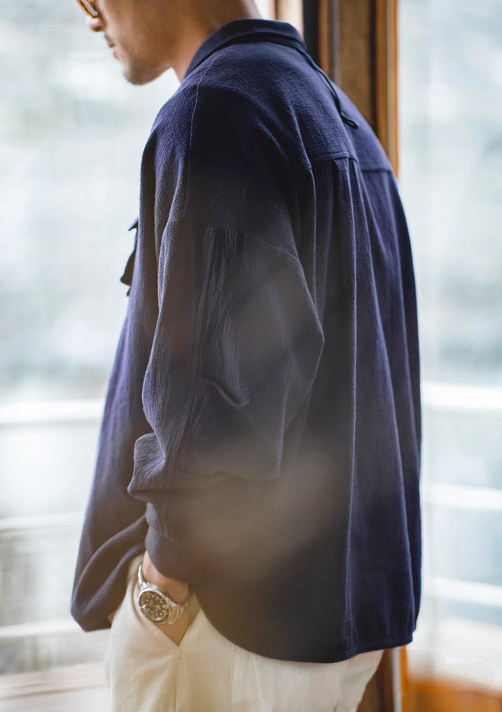 Blue textured cotton polo shirt worn by model side profile view showcasing drape, sleeve structure, and breathable fabric