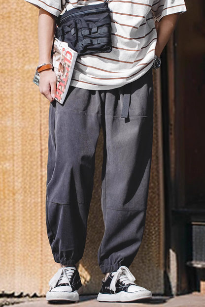 Model styling Textured Lounge Joggers in Dark Gray outdoors showcasing relaxed silhouette, elastic cuffs, and functional side pockets with casual streetwear look