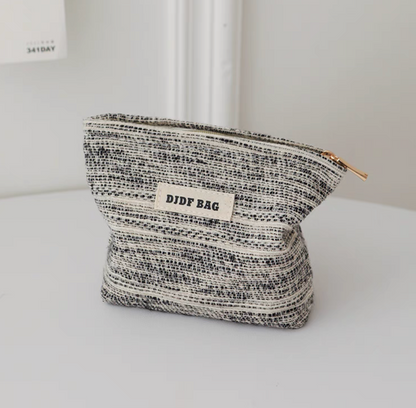 Textured Stripe Mini Cosmetic Zip Pouch in stripe pattern standing upright with front label and gold-tone zipper pull