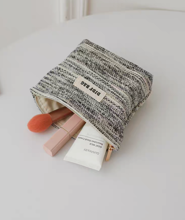 Textured Stripe Mini Cosmetic Zip Pouch in stripe pattern shown open with makeup brush, lipstick, and cream tube inside