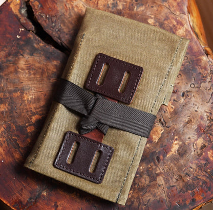 Army Green Field Companion folded canvas roll with leather buckles on wood surface.