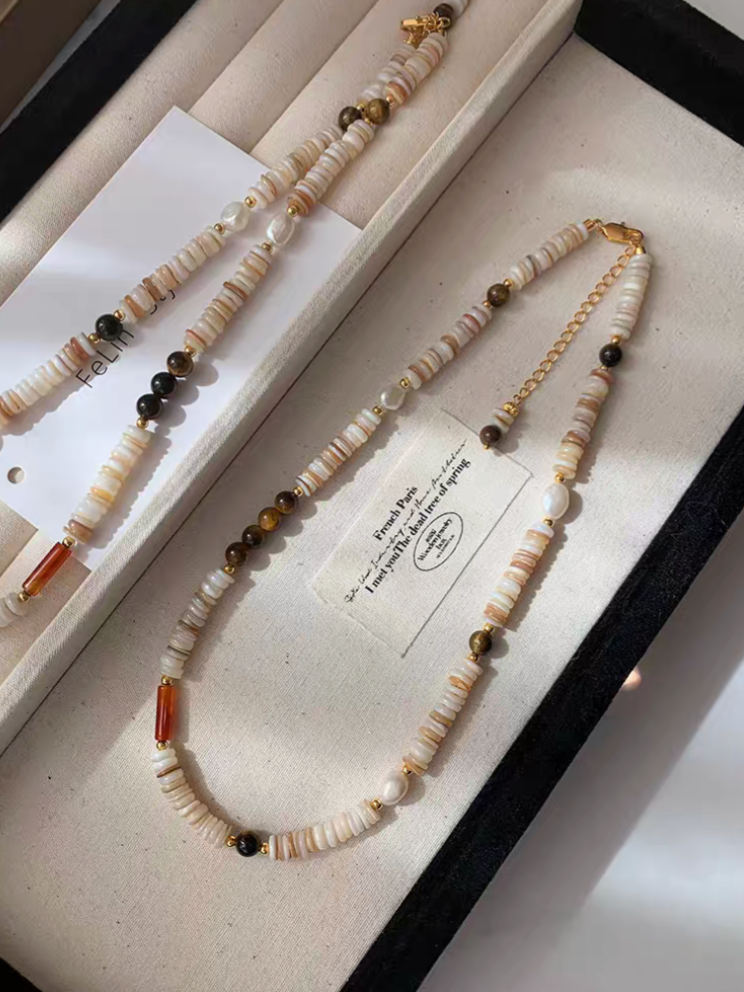 Tiger eye and shell pearl beaded choker necklace with multicolor shell disc beads, freshwater pearls, and gold accents displayed in jewelry box