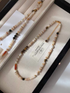 Tiger eye and shell pearl beaded choker necklace with multicolor shell disc beads, freshwater pearls, and gold accents displayed in jewelry box
