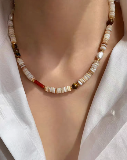Close-up of tiger eye and shell pearl choker worn on neck featuring multicolor shell beads, freshwater pearls, and gold details