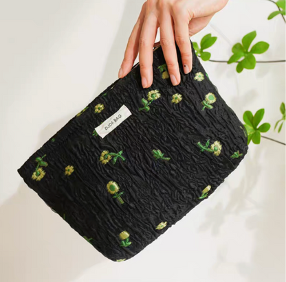 Timeless Elegance Portable Makeup Bag in black with small green flower pattern held at angle with textured fabric detail
