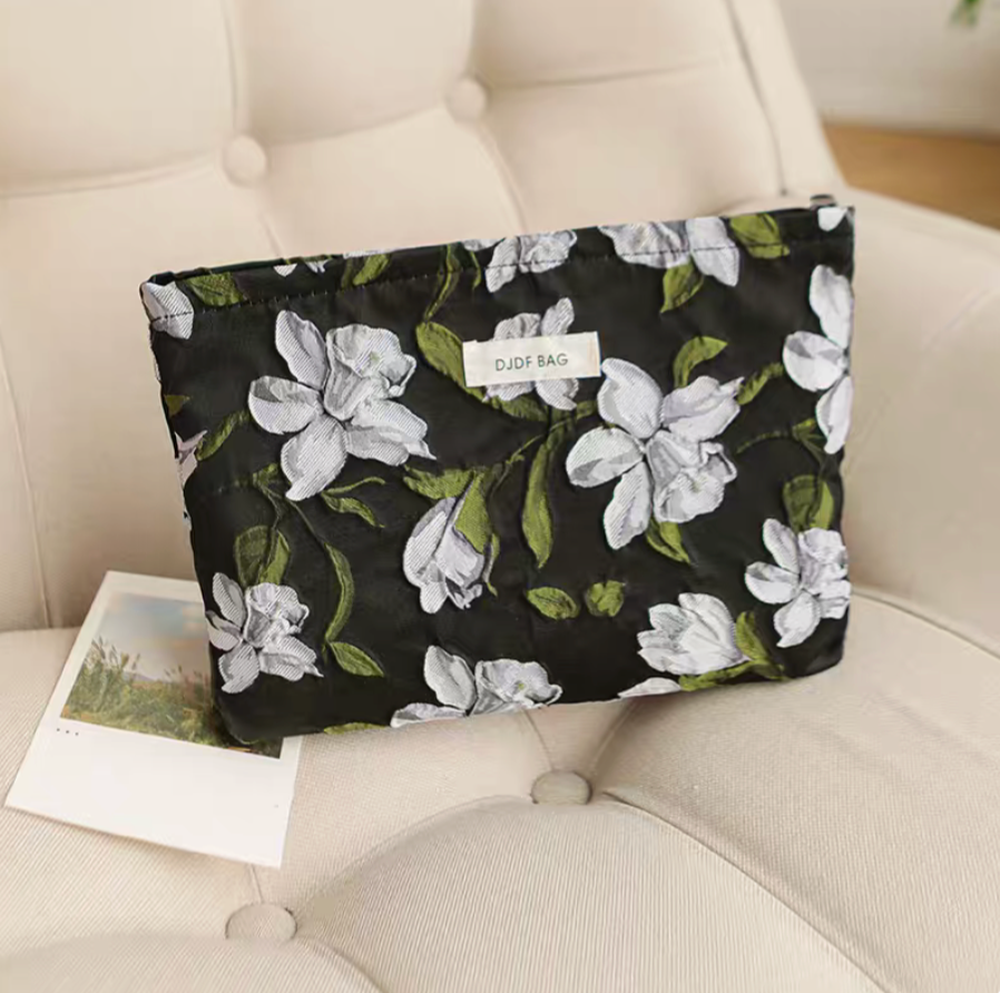 Timeless Elegance Portable Makeup Bag in camellia floral pattern placed on chair with large white flower design on dark background