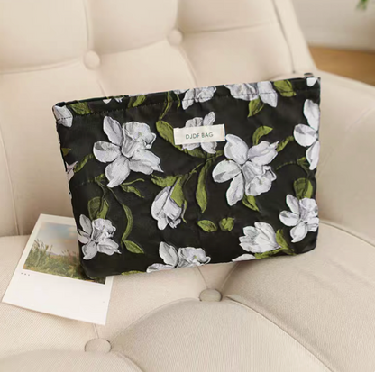 Timeless Elegance Portable Makeup Bag in camellia floral pattern placed on chair with large white flower design on dark background