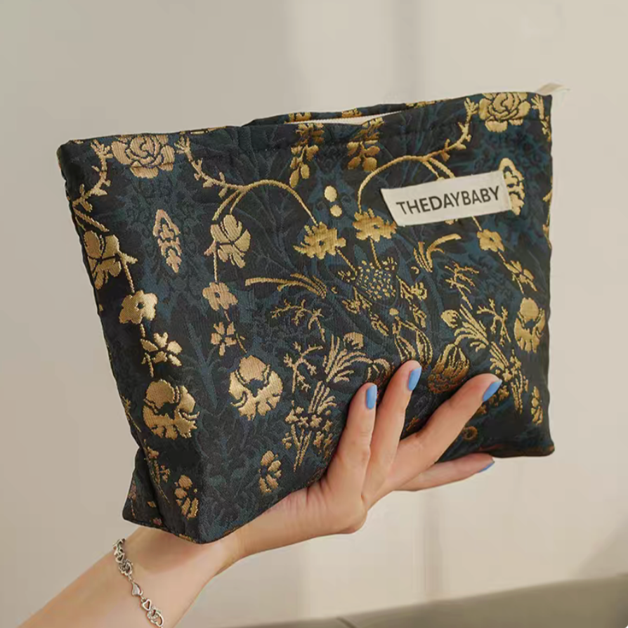 Timeless Elegance Portable Makeup Bag in dark green and gold floral pattern held in hand highlighting rich textured design
