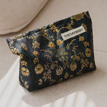Timeless Elegance Portable Makeup Bag in dark green and gold pattern placed upright on sofa with detailed floral texture visible