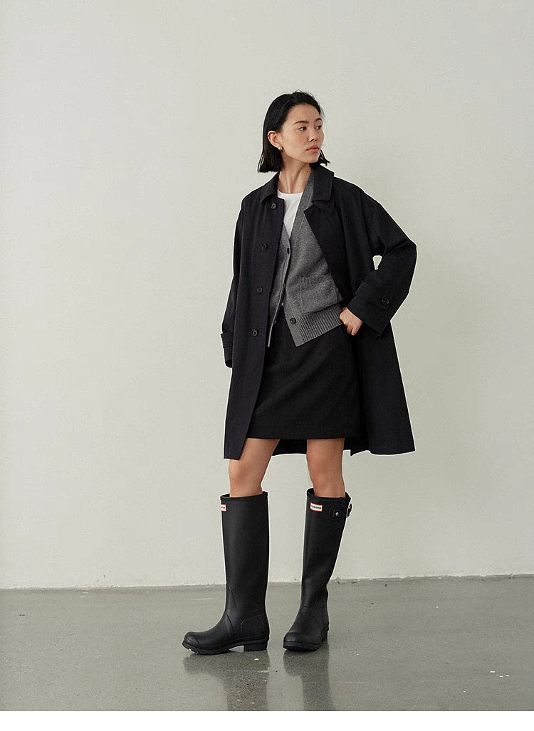 Black Timeless Trench Coat worn in angled pose highlighting tailored fit, horn button closure and clean structured design