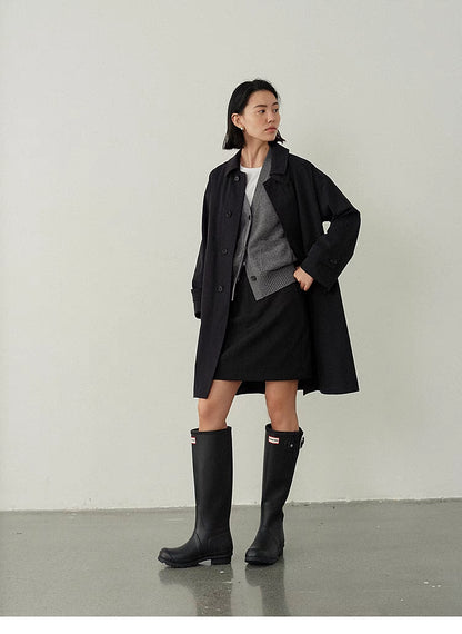 Black Timeless Trench Coat worn in angled pose highlighting tailored fit, horn button closure and clean structured design