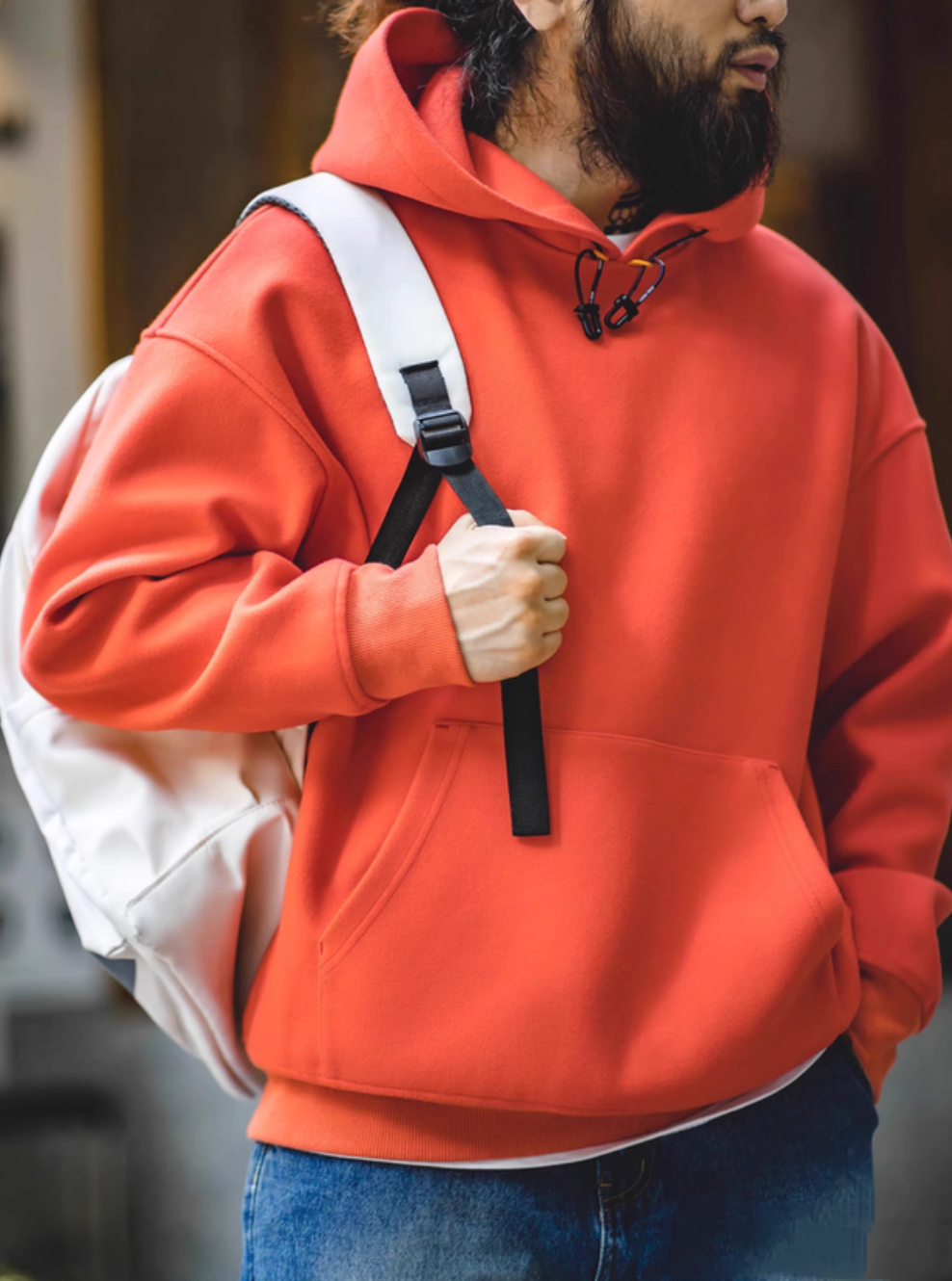 Model wearing Trailblazer Pullover Hoodie in orange with backpack in casual outdoor lifestyle styling