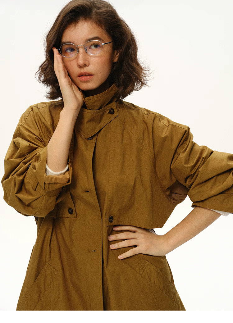 Close-up portrait of woman wearing maple brown trench with collar raised.