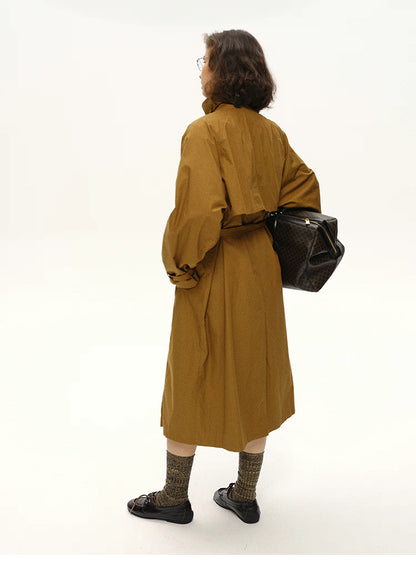 Back view of a maple brown long trench coat showing storm flap and belt.