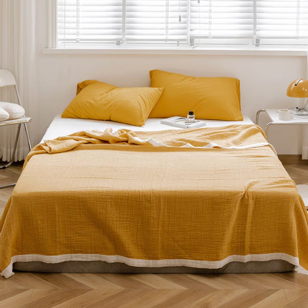 Bright yellow ripple gauze cotton quilt with zigzag edge styled on modern bed with matching pillows.