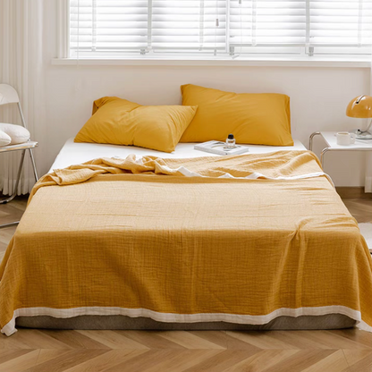 Bright yellow ripple gauze cotton quilt with zigzag edge styled on modern bed with matching pillows.
