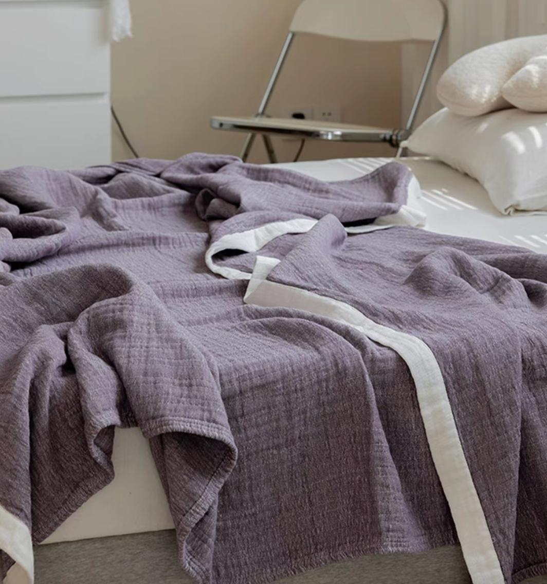 Dark coffee ripple gauze cotton quilt draped on bed with neutral pillows in modern bedroom.