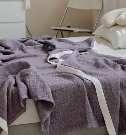 Dark coffee ripple gauze cotton quilt draped on bed with neutral pillows in modern bedroom.