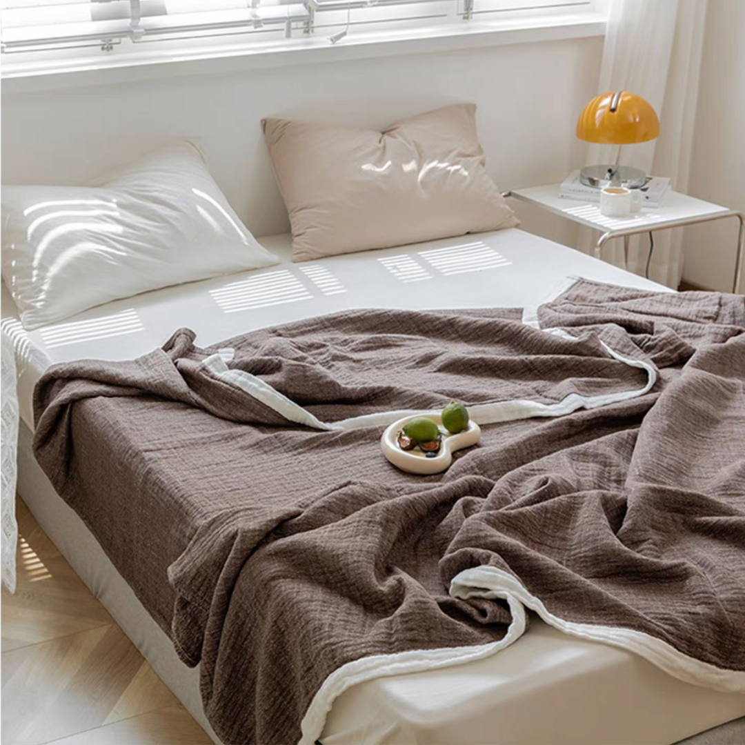 Dark coffee ripple gauze cotton quilt draped across bed with decorative tray and bedside lamp.