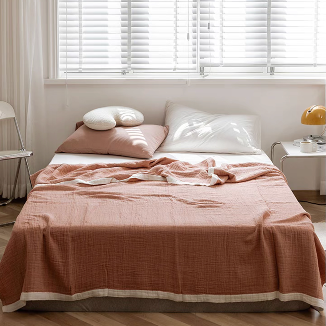 Deep pink ripple gauze cotton quilt with zigzag edge styled on modern bed with neutral pillows.