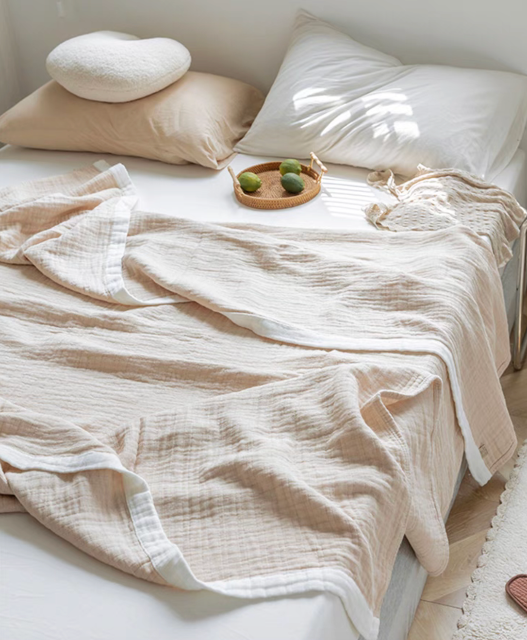 Light brown organic cotton ripple gauze quilt draped across bed with woven tray and decorative accents.