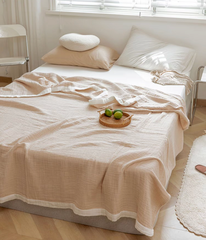 Light brown ripple gauze cotton quilt with zigzag edge styled on modern bedroom bed with neutral pillows.