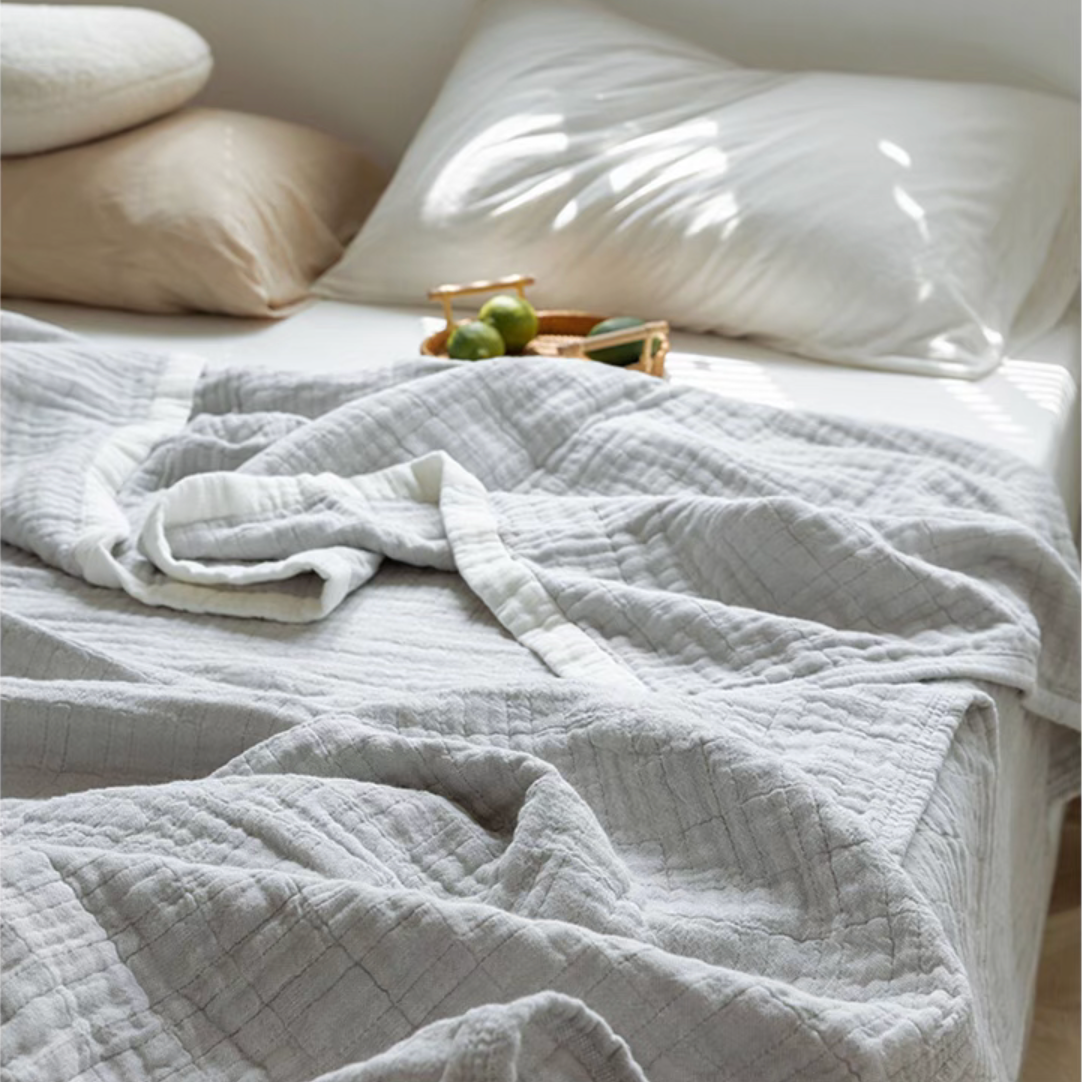 Light gray ripple gauze cotton quilt close-up showing quilted grid texture and zigzag edging.