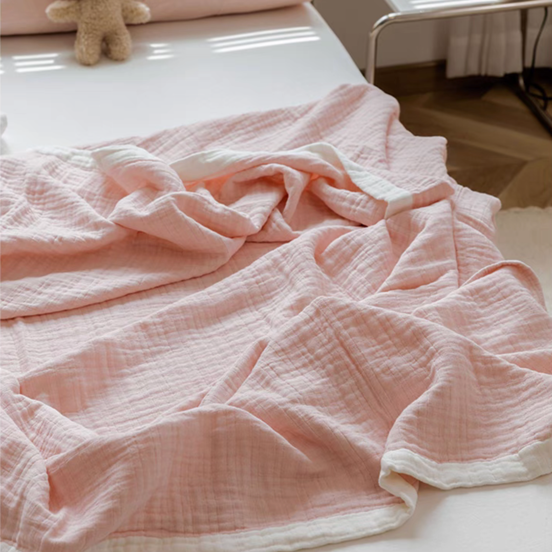 Close-up of light pink triple layer gauze cotton quilt showing soft breathable rippled texture.