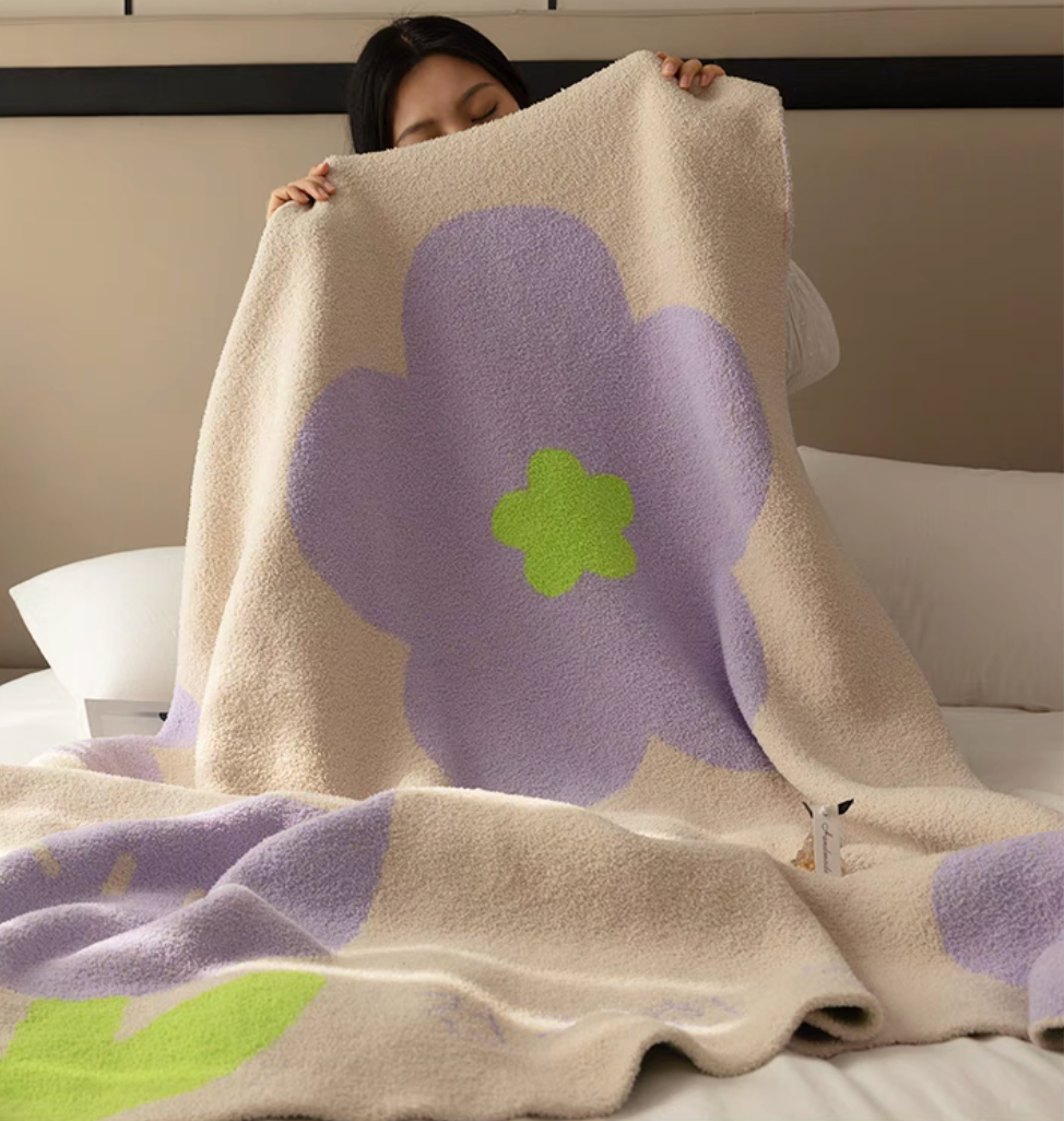 Tulip Luxe Blanket in tulip purple held over bed displaying large abstract tulip flower pattern with soft cozy finish