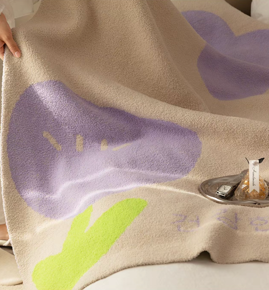 Close-up of Tulip Luxe Blanket in tulip purple showing plush texture with abstract tulip shape and soft woven fibers