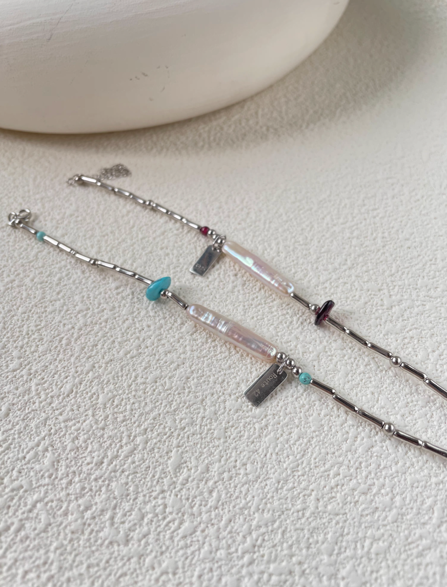 Flat lay of baroque pearl bracelets with turquoise and garnet accents showcasing natural pearls and silver chain details