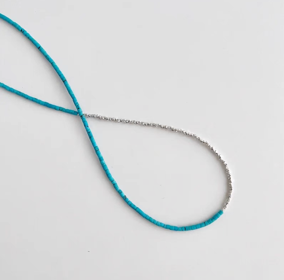 Close-up flat lay of turquoise and silver delicate choker necklace showing natural turquoise beads and fine silver chain detail