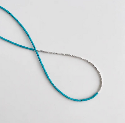 Close-up flat lay of turquoise and silver delicate choker necklace showing natural turquoise beads and fine silver chain detail