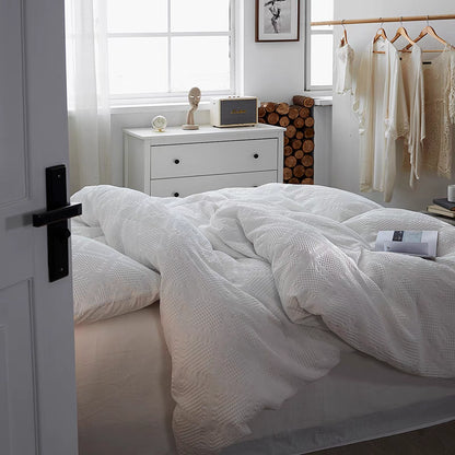 White ultra-soft organic cotton waffle weave bedding set draped on bed in bright minimalist bedroom