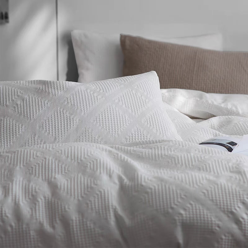 Close-up of white organic cotton waffle weave bedding set highlighting soft geometric texture and breathable cotton fabric