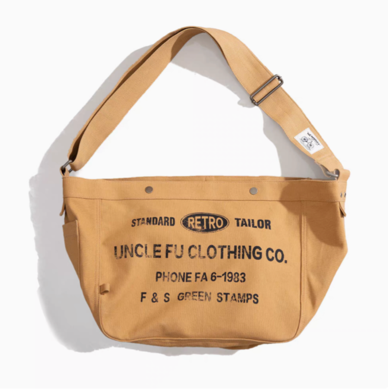 Urban Cruiser canvas messenger shoulder bag in apricot yellow front view showing Uncle Fu Clothing Co print and adjustable strap