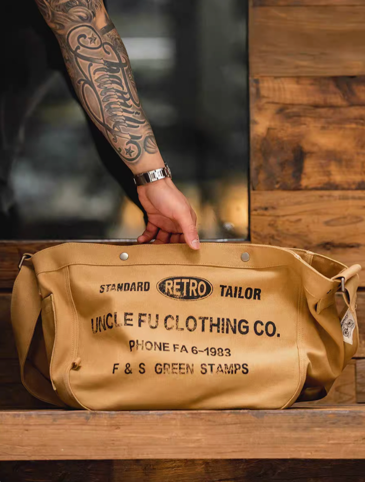 Hand holding Urban Cruiser apricot yellow canvas messenger bag top view highlighting wide opening and retro printed design