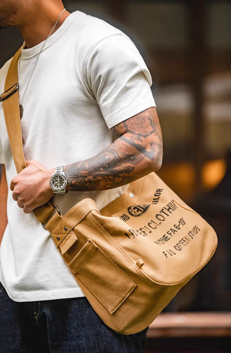 Man wearing Urban Cruiser apricot yellow canvas messenger shoulder bag crossbody style showing side pocket and adjustable strap