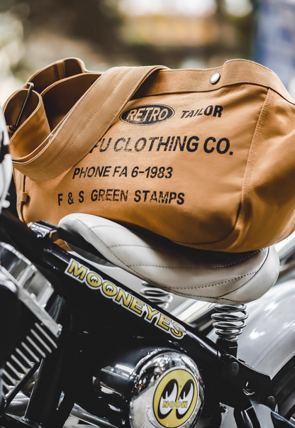 Urban Cruiser apricot yellow canvas messenger bag placed on motorcycle seat highlighting rugged vintage style and durability