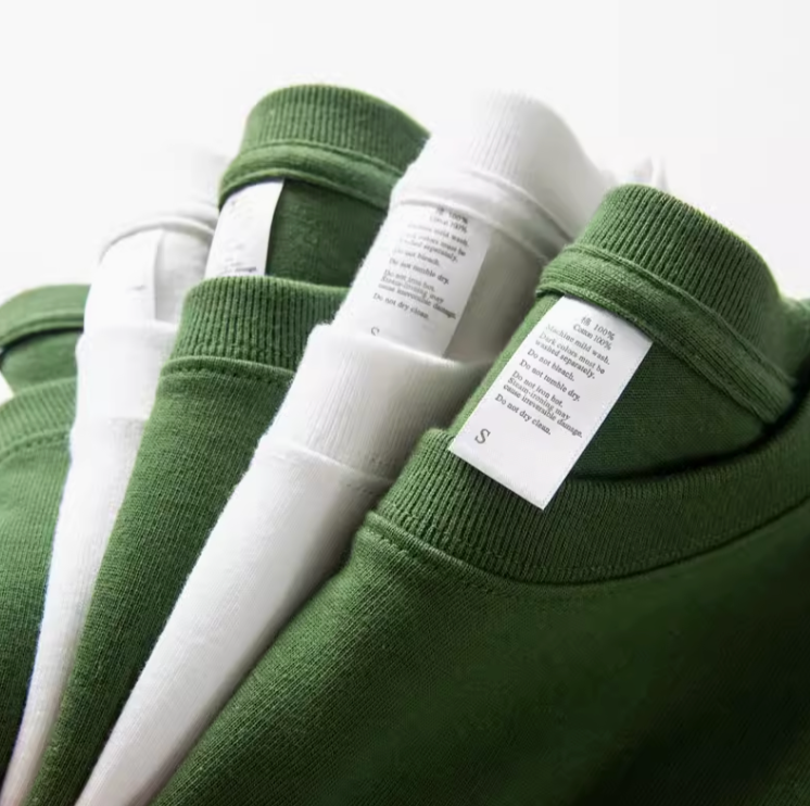 Urban Forest Tee white and avocado green stacked t-shirts with visible care labels showing cotton fabric details