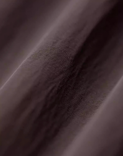 Close-up of crinkle-texture nylon fabric in dark coffee brown color showing subtle sheen and durable weave detail.