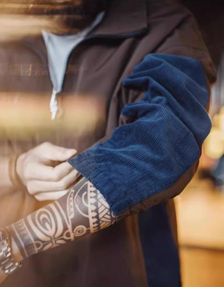 Detail shot of blue corduroy sleeve patch contrasted with brown nylon body, emphasizing the patchwork craftsmanship.