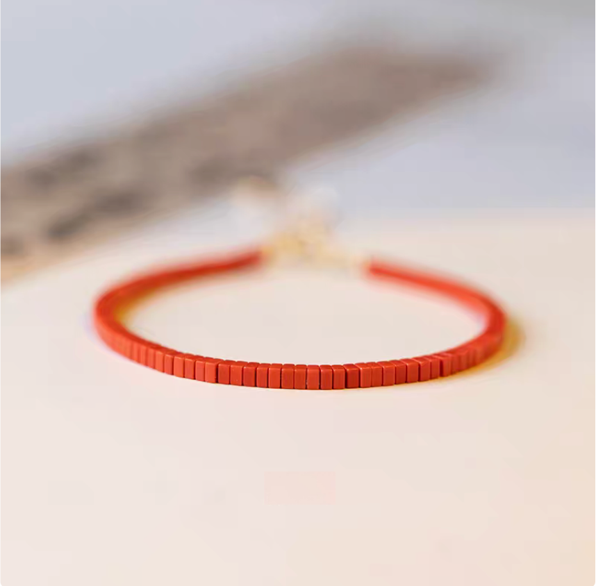 Vermilion stone vintage bracelet flat lay showing vivid red micro tile beads with clean minimalist styling on neutral background