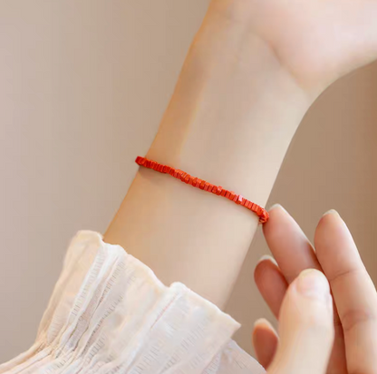 Close-up of vermilion stone vintage bracelet worn on wrist with hand gently touching highlighting bright red tile bead texture