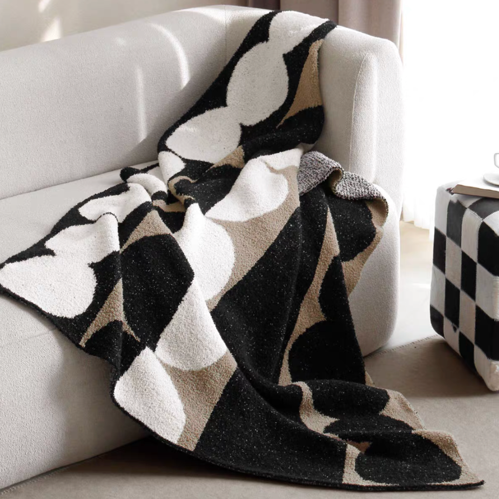 Black geometric circle plush knit throw blanket draped over armchair with bold contrast circular pattern