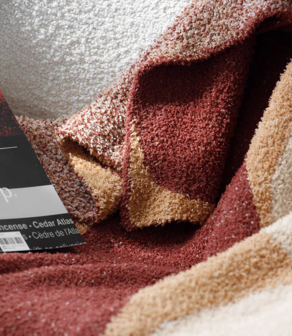 Close-up of red geometric throw blanket highlighting dense plush knit texture and circular pattern detail