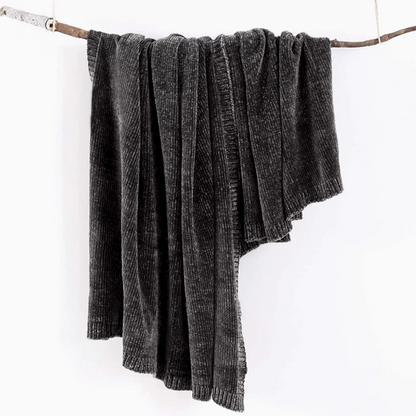 Black vertical rib chenille knit solid throw blanket hanging over a wooden branch