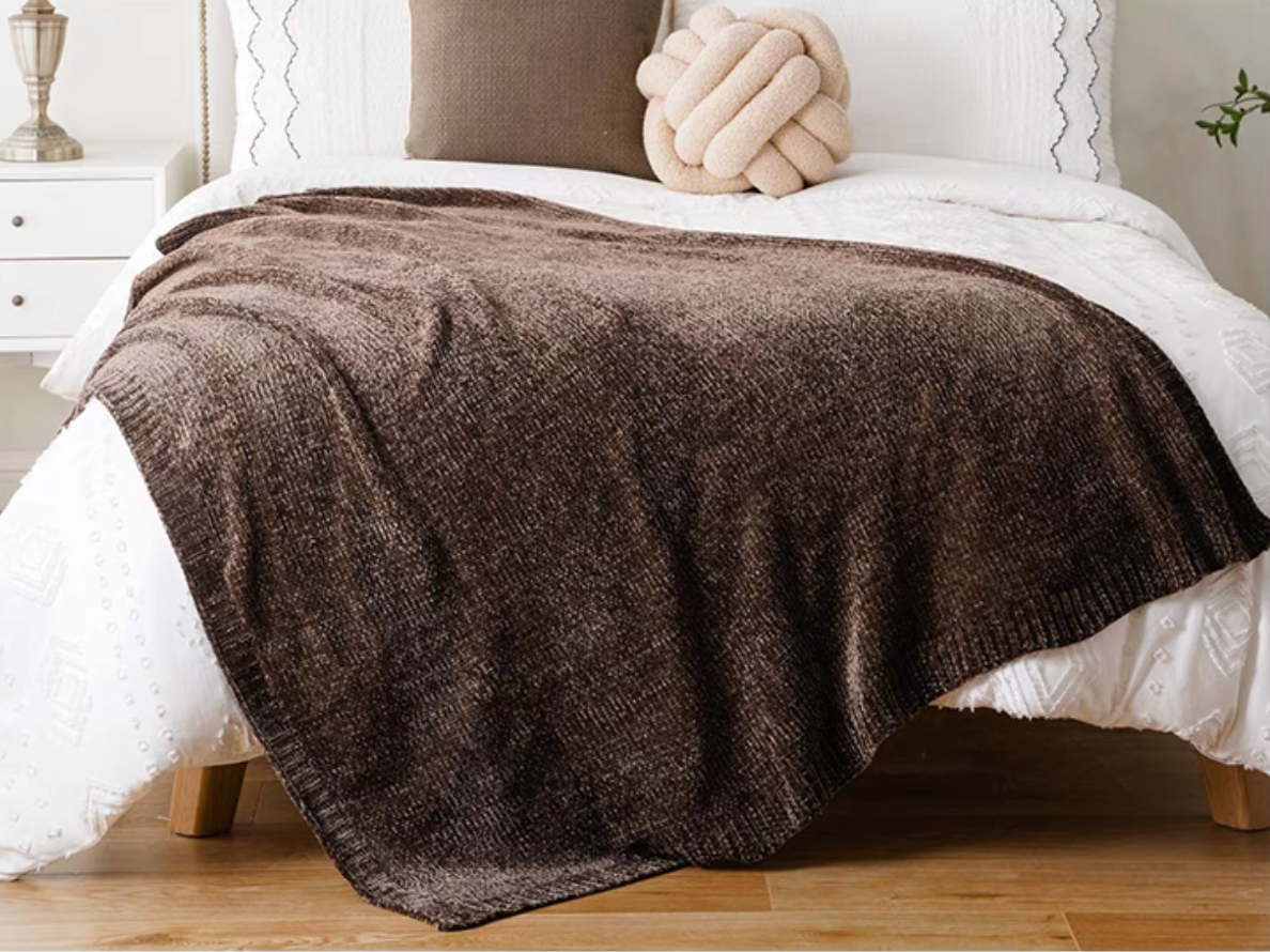 Dark brown vertical rib chenille knit solid throw blanket layered across a white bed