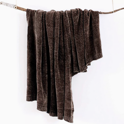 Dark brown vertical rib chenille knit solid throw blanket hanging over a wooden branch