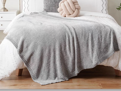 Gray vertical rib chenille knit solid throw blanket layered across a white bed